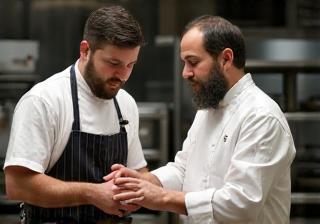 Experienced chef guiding a young cook in a professional kitchen environment